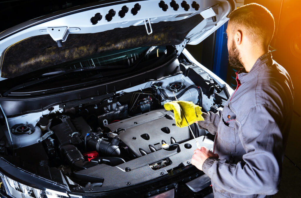 A technician measuring the oil levels of a car.