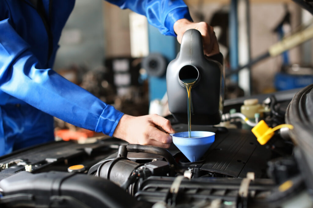 A mechanic adding oil to an engine.