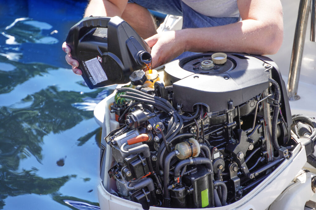 A mechanic pours engine oil into the reservoir of their maritime vehicle.