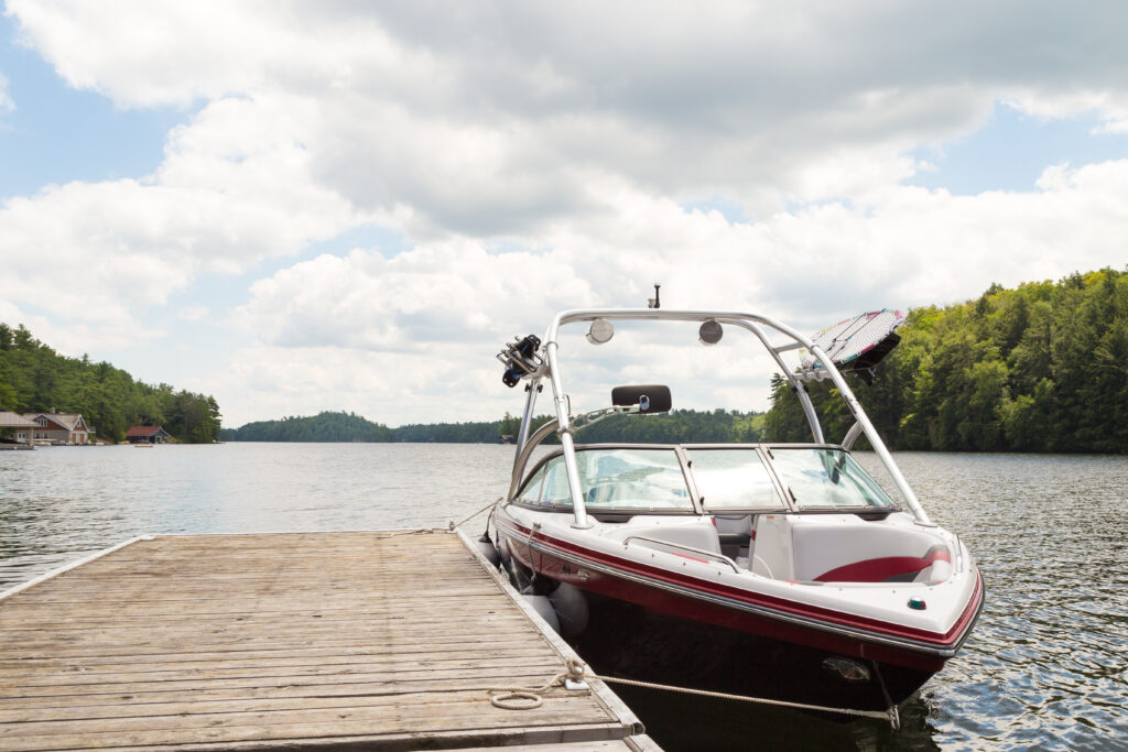 A clean boat docked to a wooden docking area. Mostly sunny day.