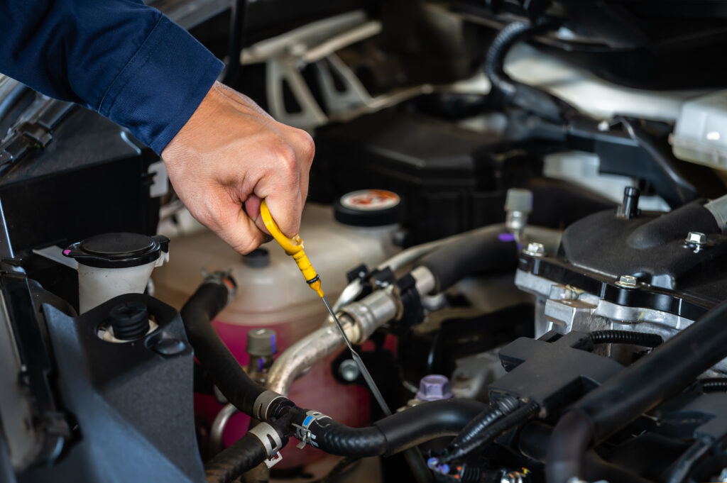 A technician checking the oil level of a car.