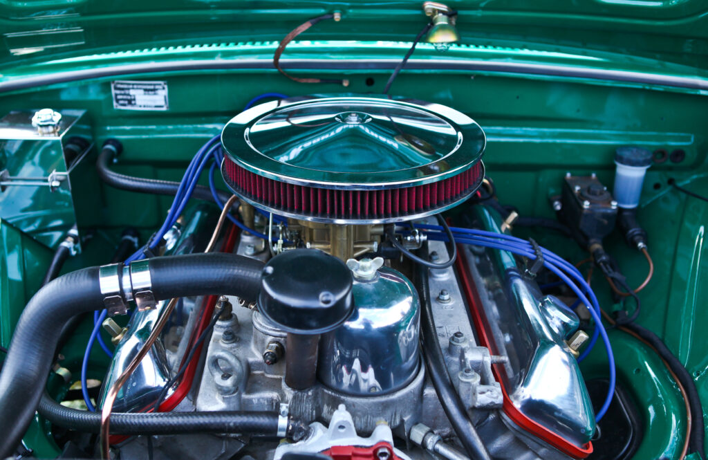 A muscle car's engine, exposed to the open air. Showing everything from electrical cables to fuel components