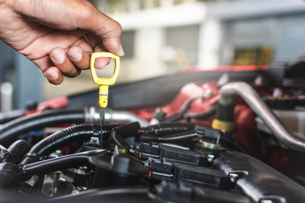 An auto technician checks the oil levels in a vehicle.