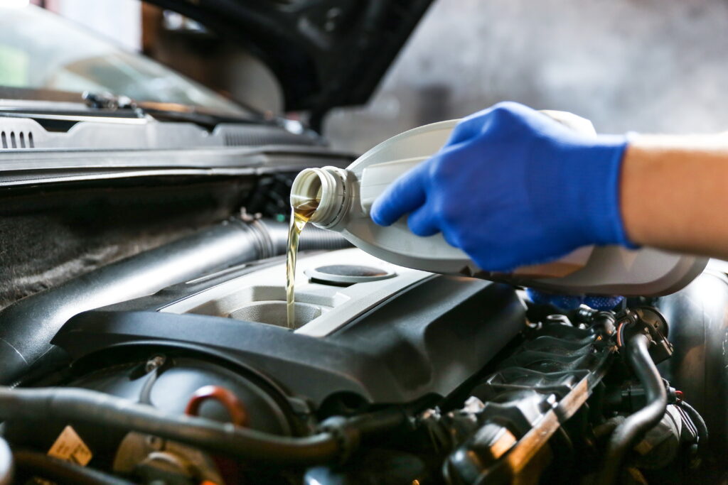 An auto worker pouring oil into an engine's reservoir. 