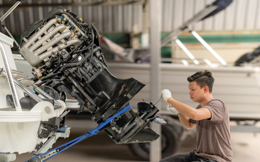 A mechanic is cleaning the engine and propulsion system of a boat. 