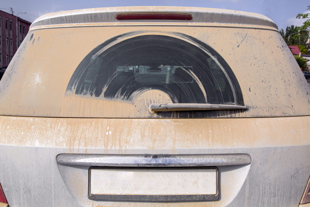 A dirty back windshield, caked with mud