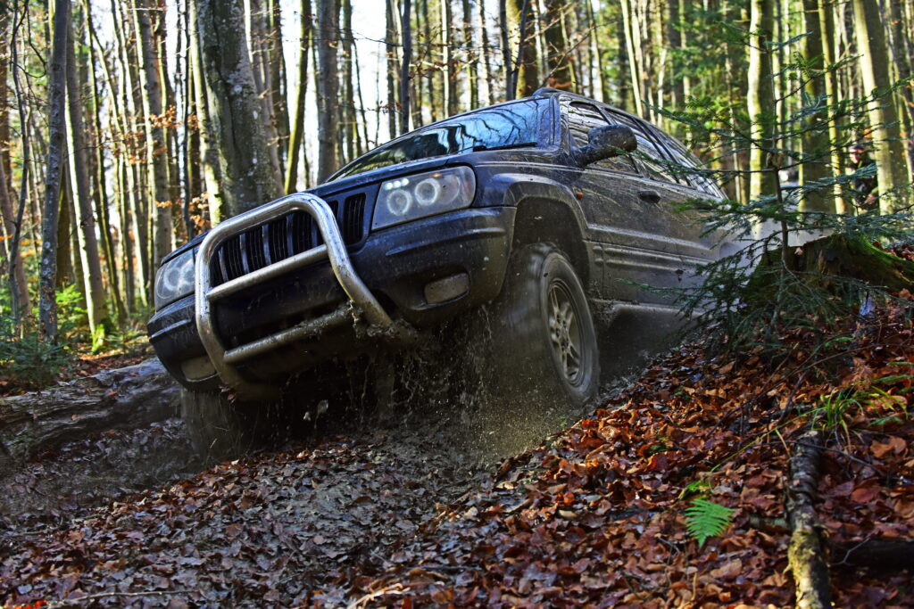 A sport utility vehicle going through a wooded area. 