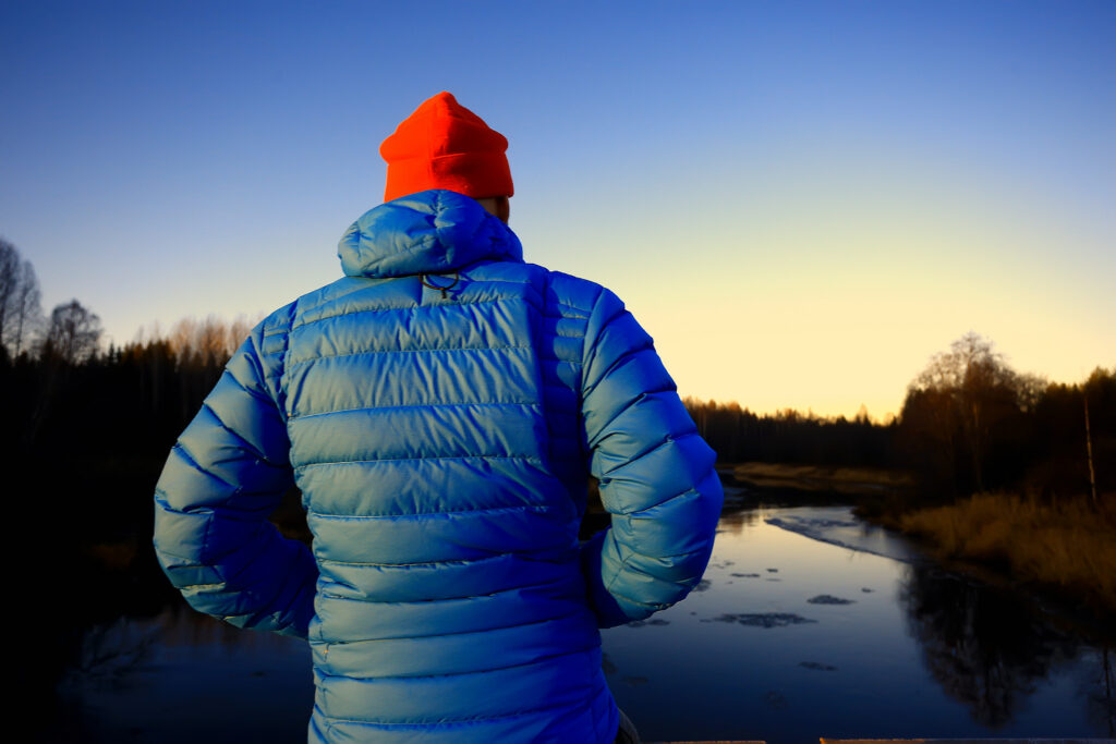 A gentleman overlooking an icy lake with winter gear on. 
