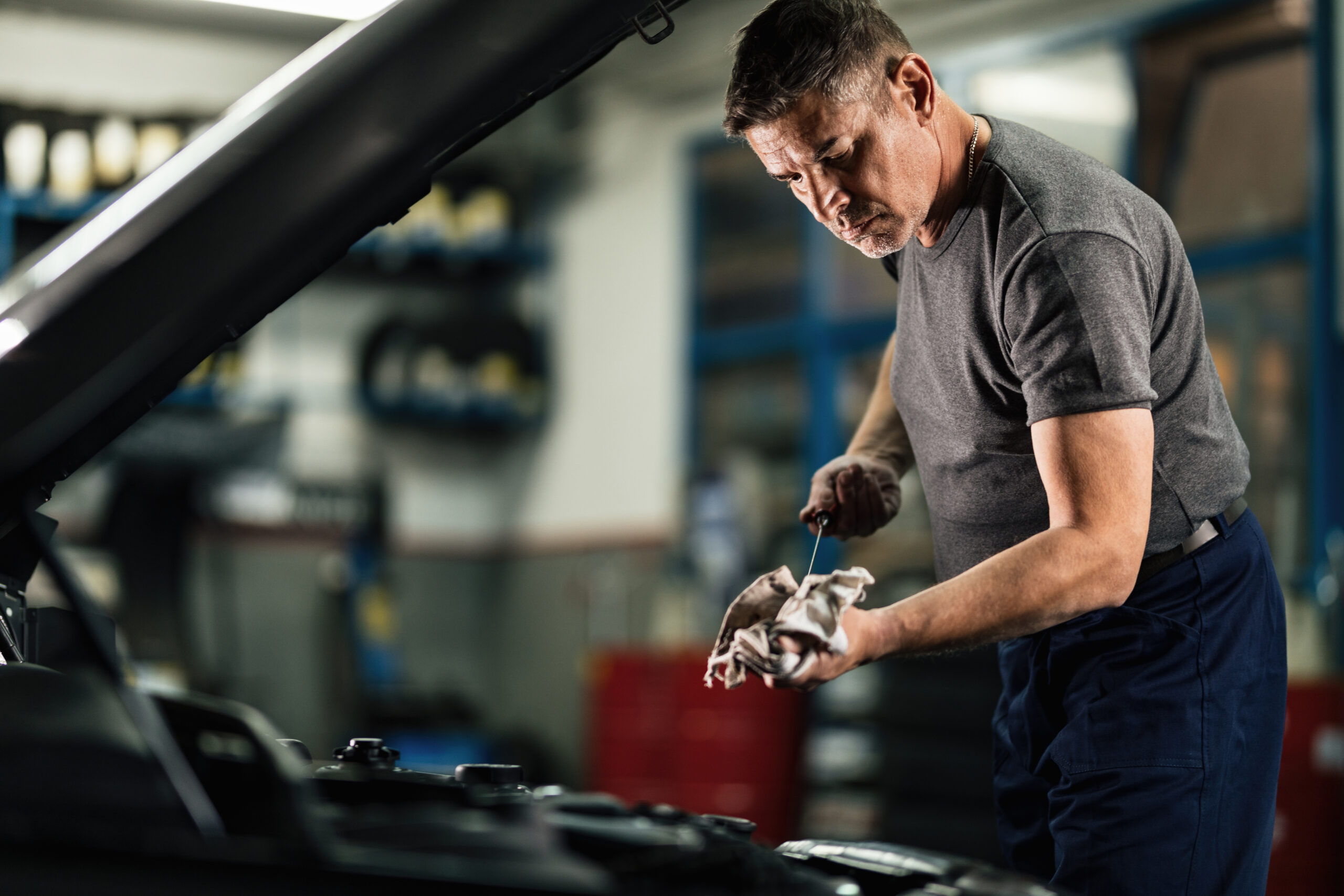 Mechanic checking oil levels in a car's engine.
