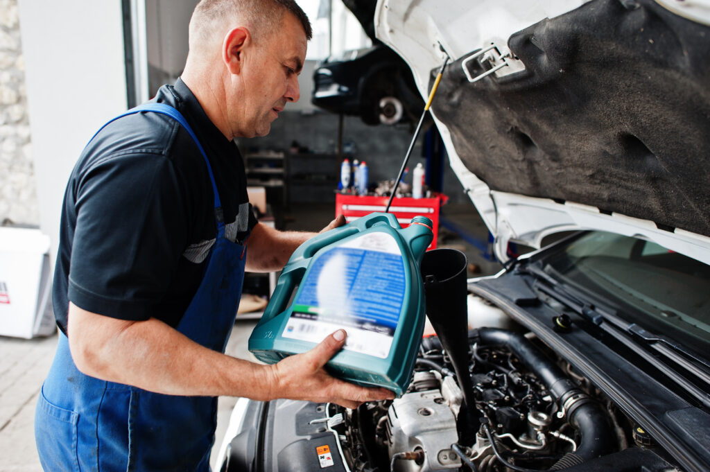 car mechanic pouring oil