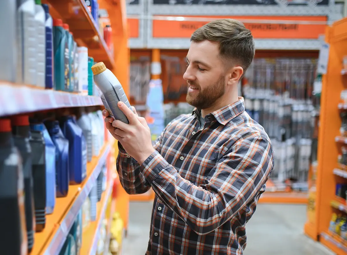 Man shopping for synthetic oil examines product from shelf