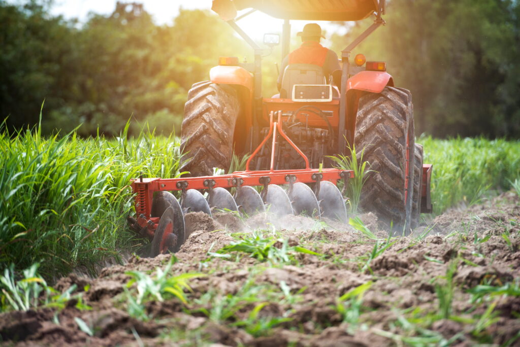 A tiller, used for planting crops, riding through a field. 